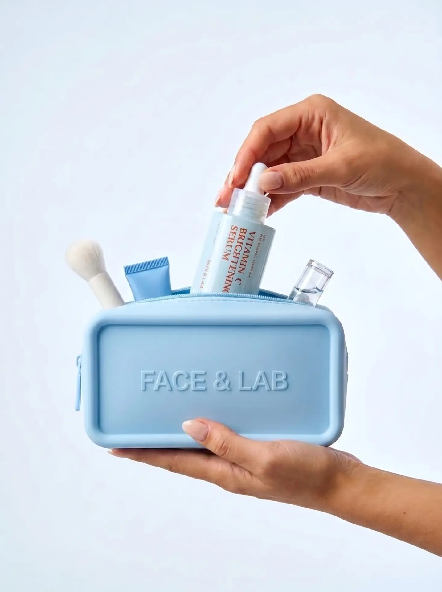 Manos sosteniendo el neceser azul de FACE & LAB con productos de skincare