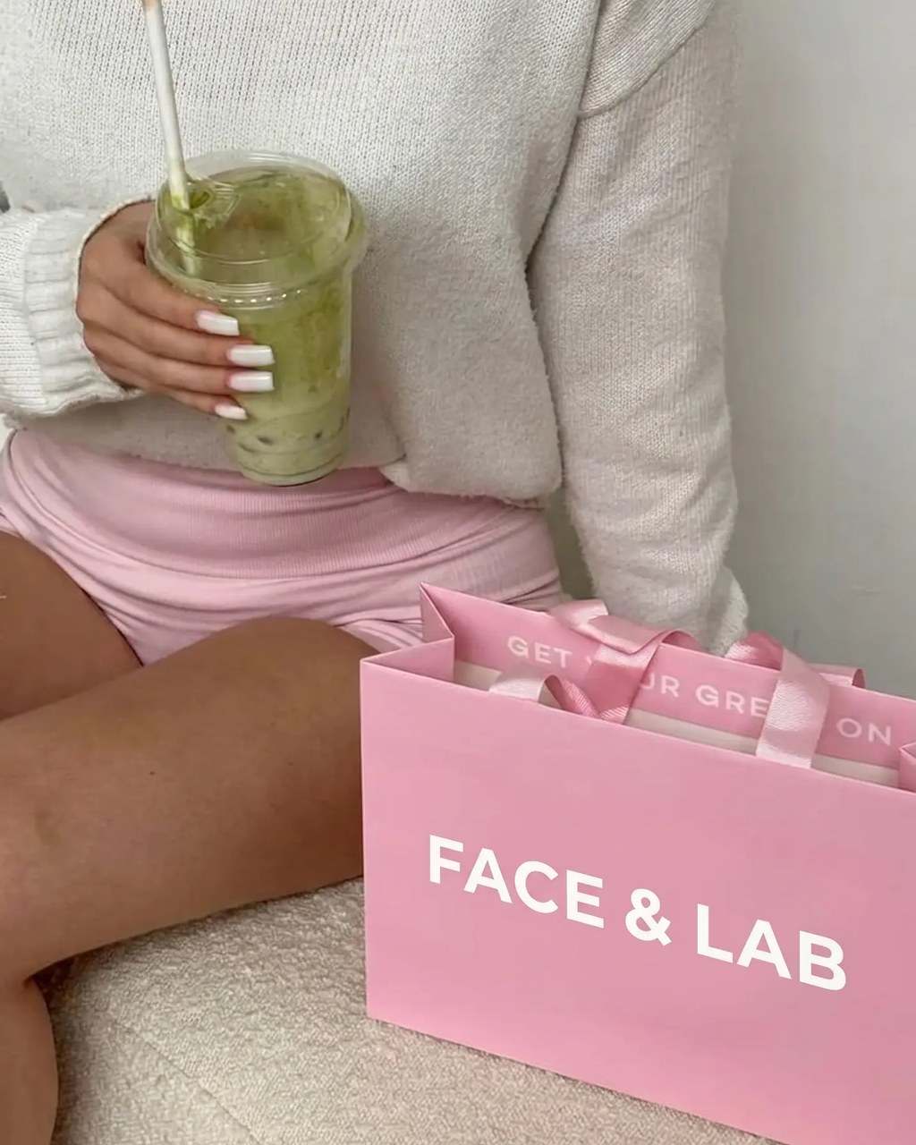 Bolsa de compras rosa de FACE & LAB junto a una clienta